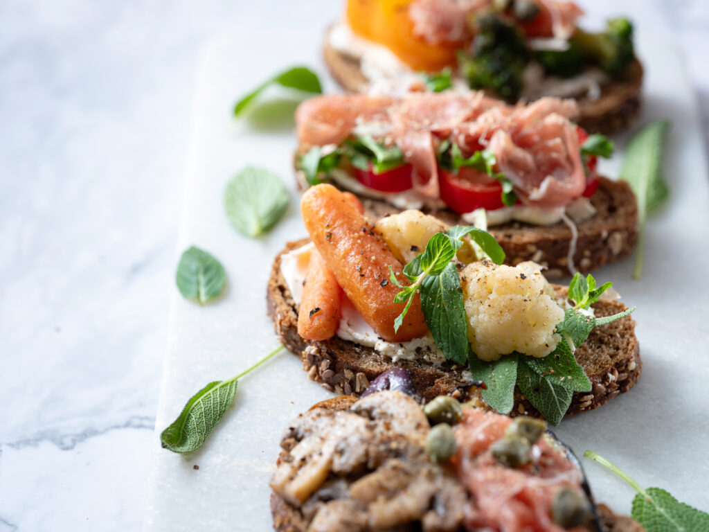 Photo de plusieurs mini-sandwiches sous un format de toast, avec des petits légumes et des herbes aromatiques.